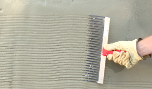 Scratch ⅛-inch deep horizontal grooves into the base coat with a raking tool,